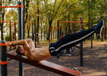 A man performing Dragon Flag calisthenics movement in an outdoor setting.