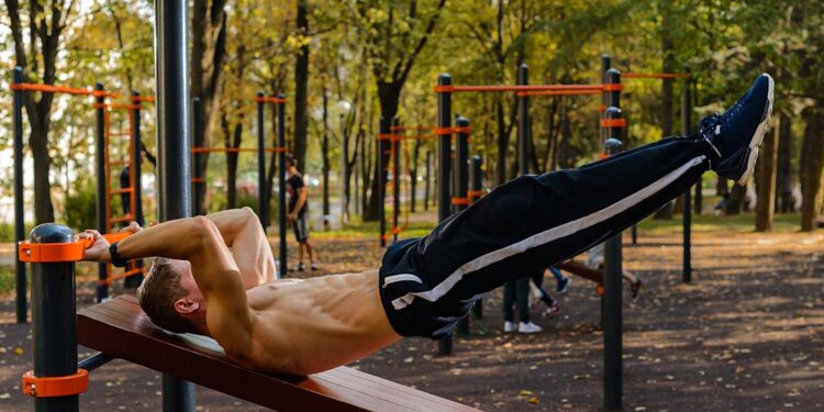 A man performing Dragon Flag calisthenics movement in an outdoor setting.