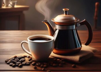 A pot and a cup of coffee on a table.